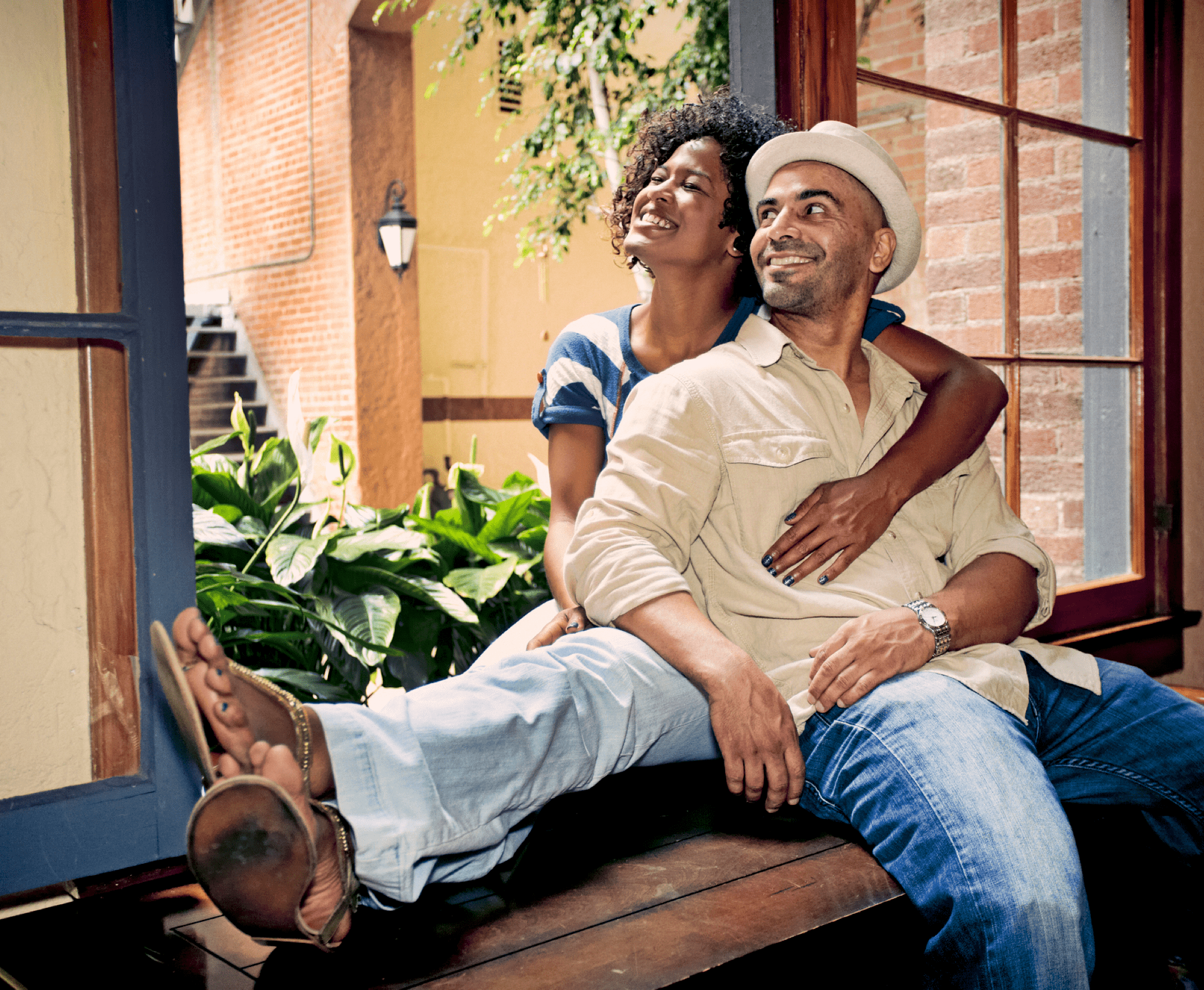 A couple sitting at a windowsill, embracing and looking out the window.